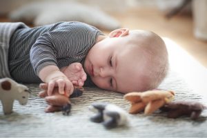 liggende baby pakt een vilten dier vast en bekijkt het