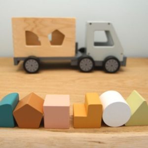 vrachtwagen van hout met puzzel blokjes op plank met grijze achtergrond